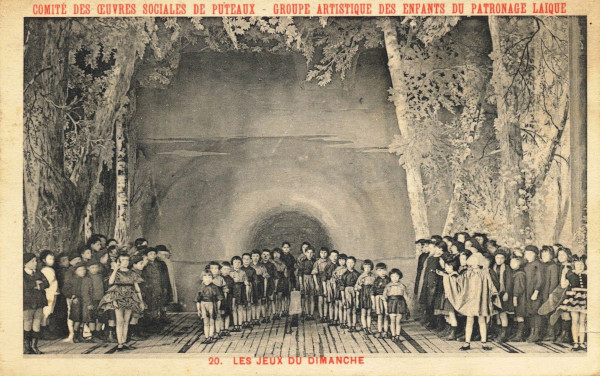 Carte postale ancienne représentant une photo de la représentation "Les jeux du dimanche" : chorale d'enfants sur scène.